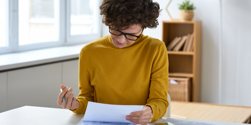 Woman looking at papers, representing reviewing guidelines to avoid predatory publishing